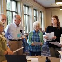 Older people listen to younger people around a table
